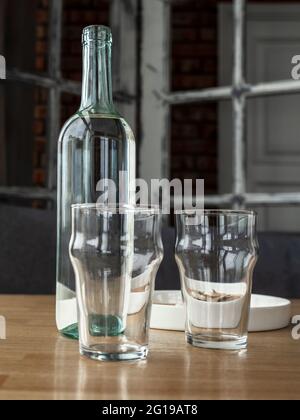 Klare Glasflasche mit Wasser oder Weißwein und zwei leeren Glasgläsern. Stockfoto