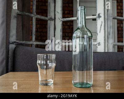 Klare Glasflasche mit Wasser oder Weißwein und zwei leeren Glasgläsern. Stockfoto