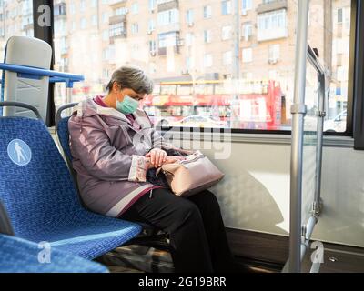 Moskau. Russland. 3. Juni 2021. Eine ältere grauhaarige Frau in einer Schutzmaske schläft während einer Fahrt in einem Stadtbus. Maßnahmen zum Schutz vor Viren Stockfoto