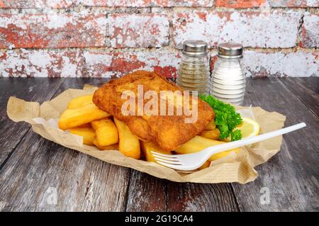 Zerschlagene Kabeljaufische und -Chips, in braunem Papier verpackt Stockfoto