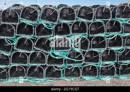 Nahaufnahme von grünen und schwarzen Fischnetzen und Fallen, die in der Abenddämmerung an der galizischen Küste in Spanien trocknen. Stockfoto