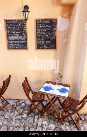 Tisch für zwei Personen im Freien aufgestellt. Das Menü wurde auf zwei Tafeln an der Wand geschrieben. Bonifacio. Korsika, Frankreich Stockfoto