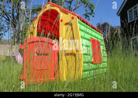 Kinderspielhaus in einem langen, mit Gras bewachsenen Garten Stockfoto