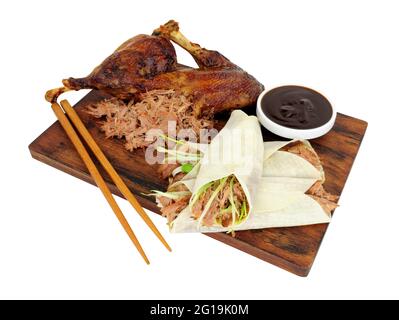 Aromatische, halbknusprige Ente mit chinesischen Pfannkuchen und Hoisin-Sauce auf einem Holzbrett, isoliert auf weißem Hintergrund Stockfoto
