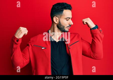 Junger hispanischer Mann in roter Lederjacke mit lächelnden Armen und Muskeln. Fitnesskonzept. Stockfoto