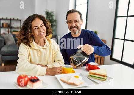 Das hispanische Paar mittleren Alters lächelte fröhlich auf dem Tisch beim Frühstück zu Hause. Stockfoto