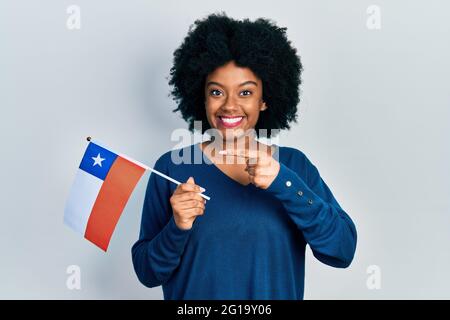 Junge afroamerikanische Frau mit der chilenischen Flagge lächelnd und mit Hand und Finger zeigend Stockfoto