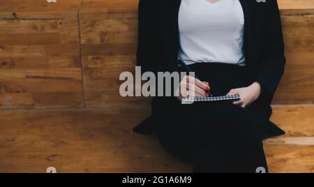 Nahaufnahme einer Frau, die im Café sitzt und auf einem Notizbuch schreibt Stockfoto