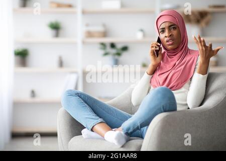 Besorgt Schwarze Muslimische Frau In Hijab Im Gespräch Auf Handy Zu Hause Stockfoto