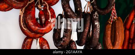 Typische spanische Würste hängen an einem Dorfstand am Lebensmittelmarkt, traditionelle Fleischprodukte Stockfoto