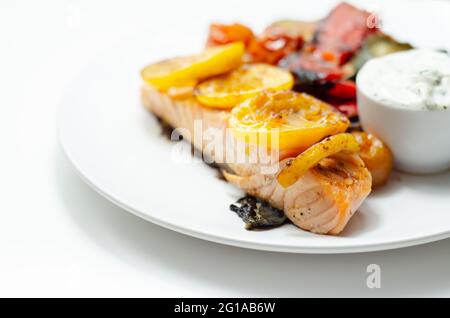 Gegrilltes Lachsfilet serviert mit gebratenem Gemüse mit Gurken und Dillsauce, gesunde Lebensmittel Stockfoto