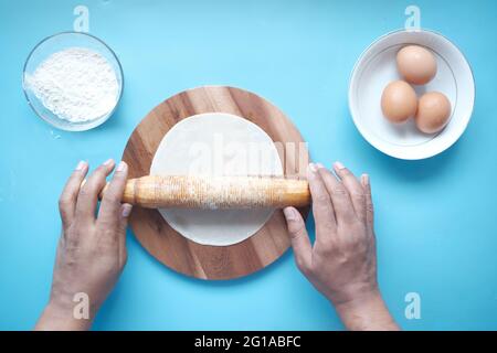 Hände backen Teig mit Nudelholz auf Holztisch, Draufsicht Stockfoto