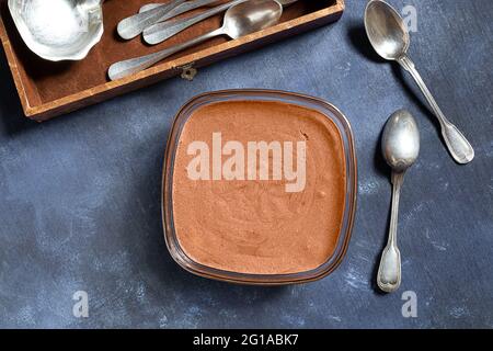 Traditionelle französische Schokoladenmousse und Silberlöffel auf blauem Hintergrund und in der Schachtel, Draufsicht Stockfoto