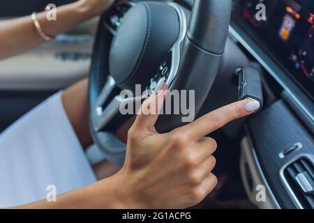 Die Frauenhand schaltet die Noppen des Wählhebels am Lenkrad. Die Hand schaltet den Autoschalthebel, Nahaufnahme eines manuellen Gangwechsels Stockfoto