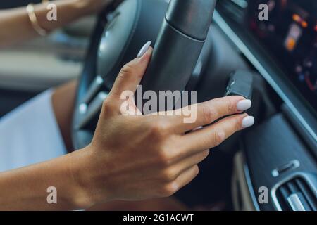 Die Frauenhand schaltet die Noppen des Wählhebels am Lenkrad. Die Hand schaltet den Autoschalthebel, Nahaufnahme eines manuellen Gangwechsels Stockfoto