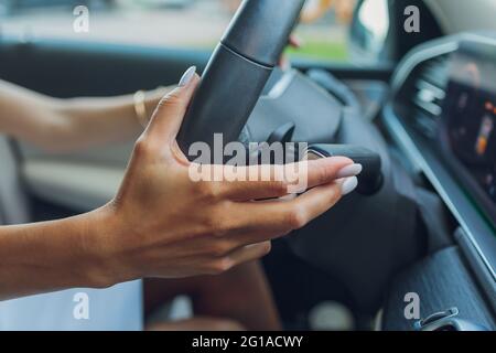 Die Frauenhand schaltet die Noppen des Wählhebels am Lenkrad. Die Hand schaltet den Autoschalthebel, Nahaufnahme eines manuellen Gangwechsels Stockfoto