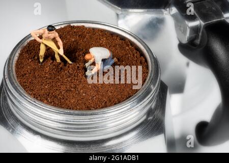 Fein gemahlener Kaffee, der durch zwei Miniaturen auf den Filter einer Mokakanne gepresst wird. Stockfoto