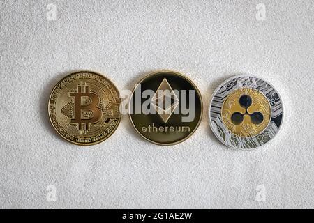 Bitcoin, Ethereum und Ripple Kryptowährung, physische Münzen auf weißem Hintergrund. Stockfoto