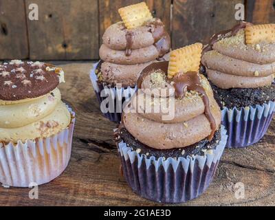 Nahaufnahme von köstlichen Cupcakes aus Schokolade, die mit Buttercreme und Keksen auf der Oberseite verziert sind Stockfoto