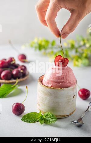 Schüssel Kirsche Eisportionierer mit Frauen Hand und frische Beeren auf weißem Hintergrund Stockfoto