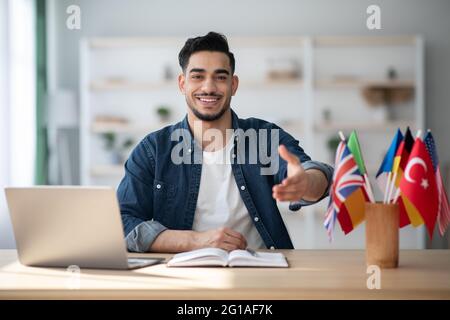 Fröhlicher arabischer Kerl Fremdsprachenlehrer, der Hand gibt Stockfoto