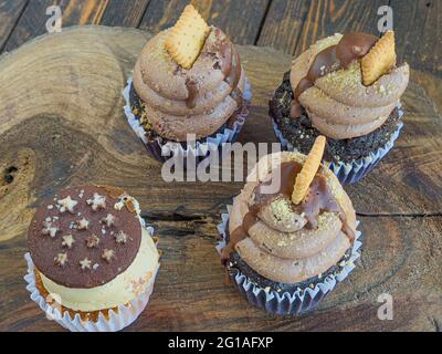 Nahaufnahme von köstlichen Cupcakes aus Schokolade, die mit Buttercreme und Keksen auf der Oberseite verziert sind Stockfoto