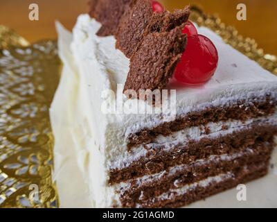 Schwarzer Waldkuchen, verziert mit Kirschen und kleinen Kuchenstücken auf einer durchbrochenen Serviette Stockfoto