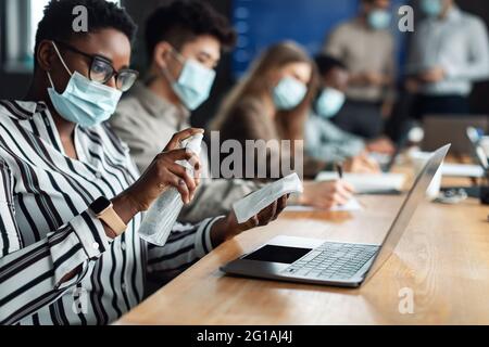 Schwarze Frau trägt medizinische Masken mit Desinfektionsmittel Stockfoto