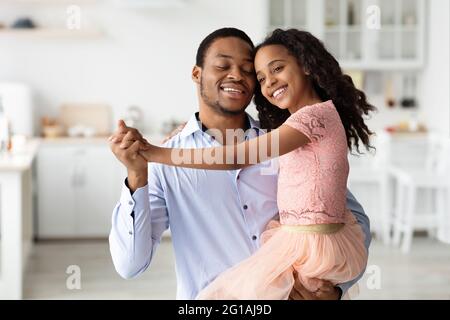 Emotionaler schwarzer Vater und Tochter tanzen zu Hause Walzer Stockfoto