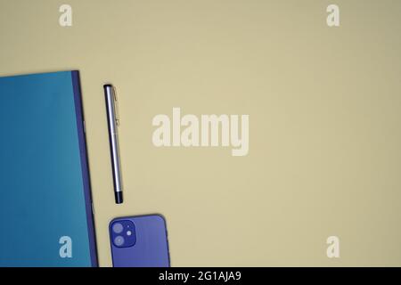 Flach im Büro, mit Stift, Handy und Notebook auf einem hellorangen Hintergrund. Business-Flat-Lay Stockfoto