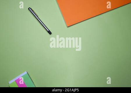 Unternehmen, Büro, Student, Bildung flach, Tischplatte. Haftnotizen, orangefarbenes Notizbuch, Stift auf grünem Hintergrund Stockfoto