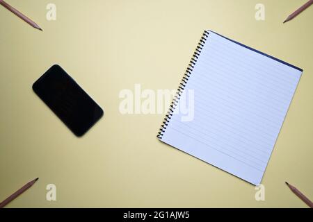 Unternehmen, Büro, Student, Bildung flach, Tischplatte. Mobiltelefon, Telefon, Spiral-Notizbuch auf gelbem Hintergrund Stockfoto