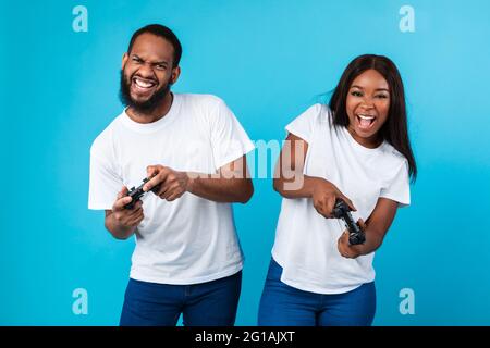 Aufgeregt schwarzes Paar spielen Videospiele zusammen mit Joysticks Stockfoto