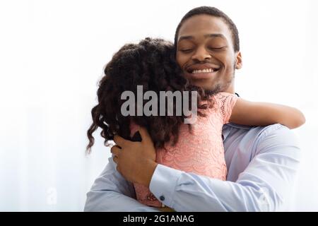 Ekstatischer afroamerikanischer Mann umarmt seine kleine Tochter Stockfoto