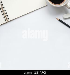 Leeres Notizbuch mit einer Tasse Kaffee, Bleistift und Radierer auf weißem Hintergrund öffnen, Platz für Text kopieren, Ansicht des Arbeitsbereichs von oben. Stockfoto