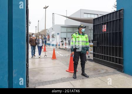 Am 2021. Juni wird über den neuen Präsidenten Perus abgestimmt. Peruanischer Polizist mit Covid-Maske am Eingang des Wahllokalen in Lima. Stockfoto