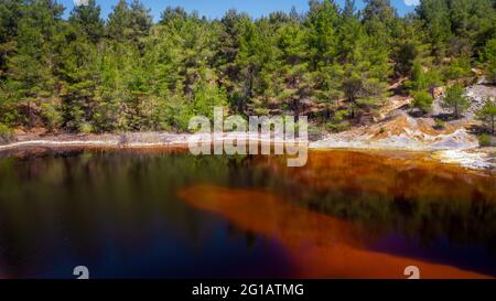 Ufer eines giftigen roten Sees in einer verlassenen Tagebaumine. Seine Farbe leitet sich von hohen Konzentrationen von Säure und Schwermetallen ab Stockfoto