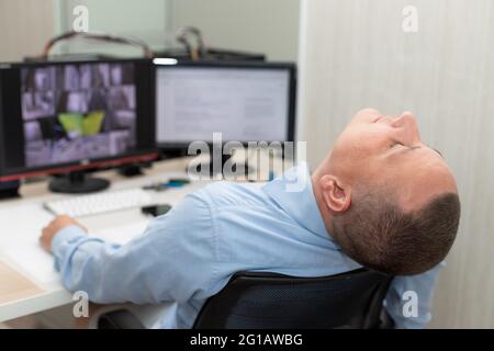 Der Wachmann schläft am Arbeitsplatz im Überwachungsraum Stockfoto