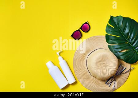 Strohhut, rosa Sonnenbrille und Palmblatt auf gelbem Hintergrund. Kreatives Minimalkonzept. Draufsicht Flat Lay Stockfoto