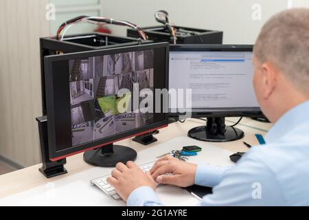 Seitenansicht des Wachschutzes, der CCTV-Kameras überwacht Stockfoto