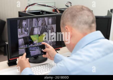 Mann, der mehrere Monitore im Überwachungsraum fotografiert Stockfoto