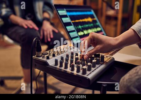 Hand der jungen Frau, die den Klang wil.e anpasst, die Musik im Studio aufnimmt Stockfoto