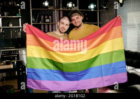 Junge liebevolle homosexuelle Paar mit Regenbogenfahne Stockfoto