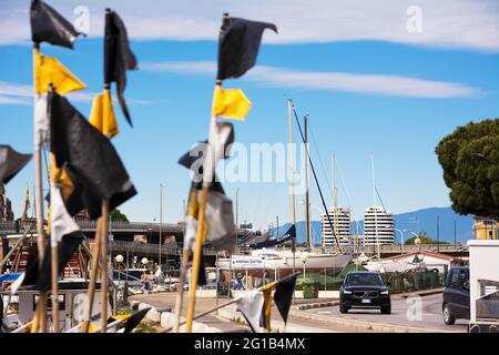 Pescara, Italien - 22. Mai 2021: Hafengebiet von Pescara mit den Flaggen der Fischerbojen und im Hintergrund die Gebäude der Camuzzi-Türme Stockfoto