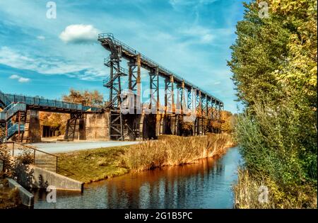 Brückenpromenade am alten Emscher inmitten des Landschaftsparks Duisburg Nord - Industriemaschinen und rostige Komponenten - Eisenwerke. Stockfoto