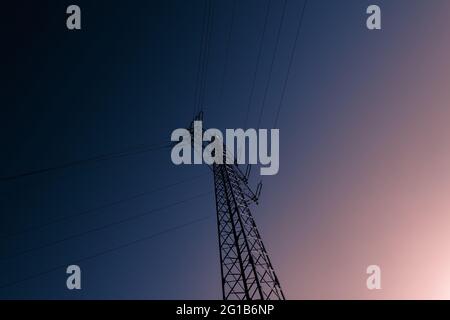 Im Sommer verzweigt der Strom bei wolkenlosem Himmel in minimalistischem Stil in freier Natur. Konstruktion für die Aufhängung einer Stromleitung. Stockfoto