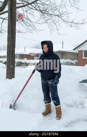 Familie oder Leute, die den Bürgersteig während des harten Winters wegen des polaren Wirbels oder Supersturms, der Toronto im Jahr 2014 traf, vom Schnee räumen. Stockfoto