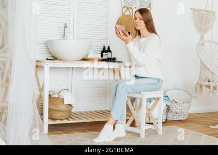 Frau, die neben dem Waschbecken sitzt und sich schminkt Stockfoto