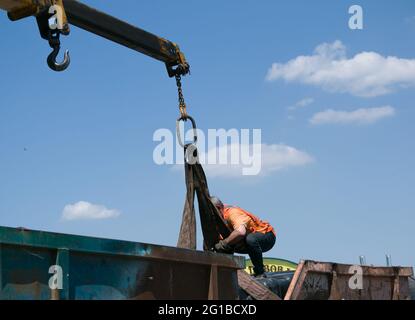 Dnepropetrovsk, Ukraine - 05.28.2021: Müllcontainer mit einem Kran in einen LKW laden. Slinger funktioniert. Stockfoto