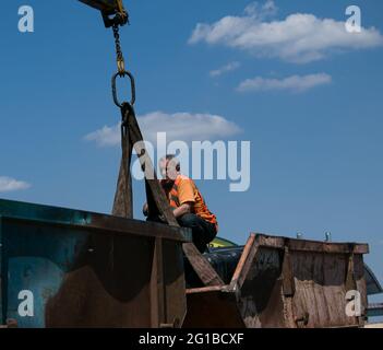 Dnepropetrovsk, Ukraine - 05.28.2021: Müllcontainer mit einem Kran in einen LKW laden. Slinger funktioniert. Stockfoto